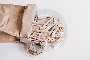 Wooden clothespins in paper bag with rope on white background. View from above. Place for your text