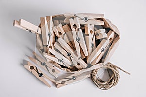 Wooden clothespins in paper bag with rope on white background. View from above. Place for your text