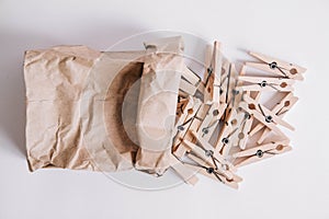 Wooden clothespins in paper bag on white background. View from above. Place for your text