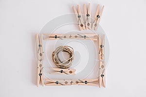 Wooden clothespins with rope on white background which are composed in the form of a photo camera icon. View from above. Place for