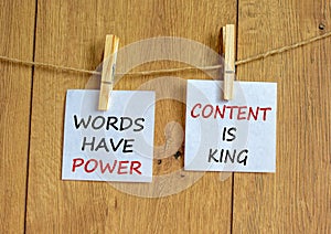 Wooden clothespins with white sheets of paper. Text `words have power, content is king`. Beautiful wooden background. Business
