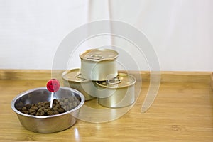 A wooden coffee tray with dry and canned cats food and a red candle on the white background. birthday cats concept. pets food.