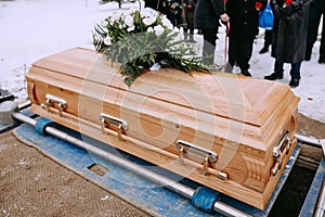 A wooden coffin with beautiful flowers arrangement stands at the cemetery