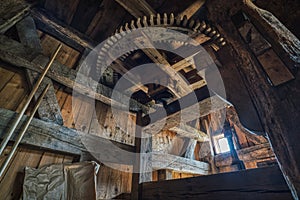 A wooden cog of an historical wind mill. Industrial interior with a toothed windmill gear, part of a milling or grinding machine