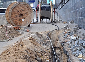 Wooden coil of electric cable and optical fibres in the digging on the street