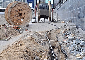 Wooden coil of electric cable and optical fibres in the digging trench on the construction site photo