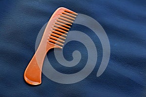A wooden comb on a nevy blue background