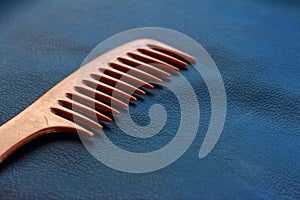 A wooden comb on a nevy blue background