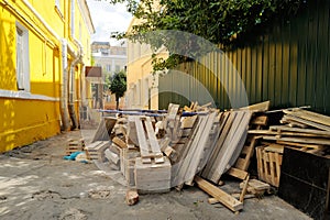 Wooden construction waste near fence and yellow wall