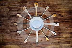 Wooden cooking spoons in shape of a clock on textured table, vintage style