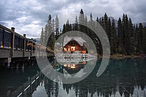 Wooden cottage glowing with pine forest and bridge reflection on Emerald lake at Yoho national park