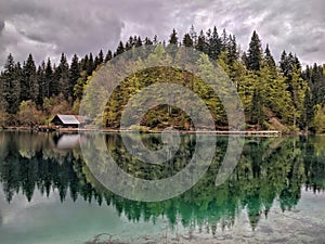 Wooden cottage on mirroring lake reflection in the woods
