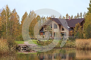 Wooden cottage on shore of autumn forest lake