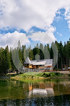 Wooden cottage on the shore of a lake on the edge of a coniferous forest