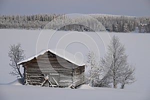 Wooden cottage on the side of a frozen lake covered with snow