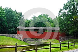 A wooden covered bridge spans a creek deep in the forest