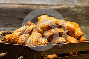 Wooden crate with delicious, fresh croissants isolated. French breakfast concept