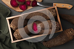 Wooden crate with whole, cut red beets and knife on table, flat lay