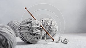 Wooden crochet hook and balls of gray yarn