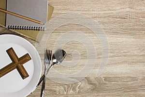 A wooden cross with Bible over the wooden table.