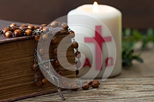 Wooden cross with bible, rosary and paschal candle, easter religious concept photo