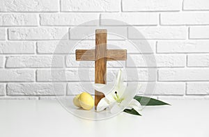 Wooden cross, Easter eggs and blossom lily on table