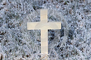 Wooden cross with ice covered grass background