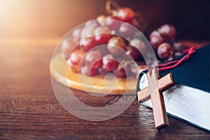 Wooden cross lean on holy bile over grape on wood plate