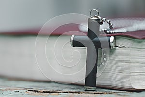 The wooden cross over opened bible on wooden table