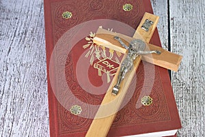 the wooden cross over opened bible on wooden table with window light, vintage tone