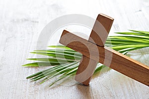 Wooden cross and palm on light background, palm sunday concept