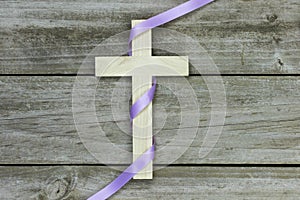 Wooden cross with purple ribbon on rugged wood background