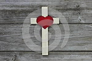 Wooden cross with red heart on rugged wood background
