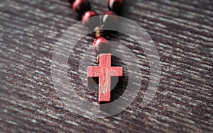 Wooden cross, rosary on wooden background. Symbol of Christianity and faith. Prayer. Concept Palm Sunday, Good Friday, Easter.