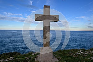 Wooden cross standing on the edge of a cliff with a dramatic sky backdrop