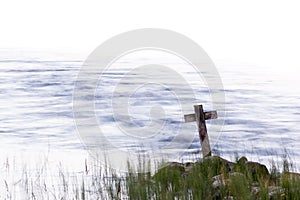 Wooden cross standing on the shore with streaming water