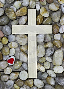 Wooden cross surrounded by stone background with red heart