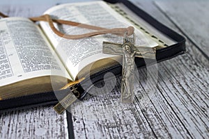 Wooden cross on top of an open bible and wood table. Copy space