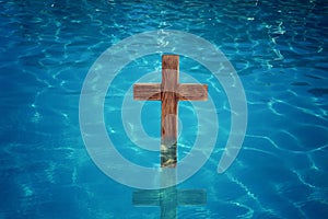 Wooden cross in water for religious ritual known as baptism photo