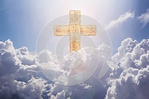 wooden cross on white cloudy sky against sunlight