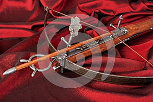 Wooden crossbow close-up on crimson silk background