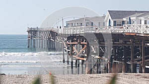 Wooden Crystal pier on piles with white cottages, California ocean beach, USA.