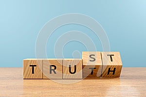 Wooden cube block flip over word TRUTH to TRUST on wood table, 3D render