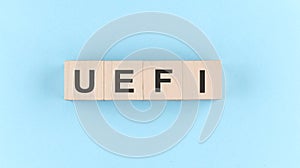 Wooden cube block with text UEFI Unified Extensible Firmware Interface on blue background