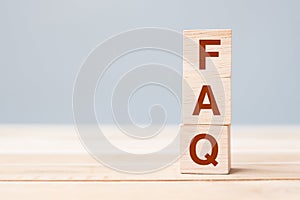 Wooden cube blocks with FAQ text frequently asked questions on table background. Financial, marketing and business concepts