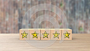 Wooden cube cartoon five yellow star review on blur wall of bricks. Service rating, satisfaction concept. reviews and comments