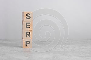 wooden cube on a concrete surface with text serp. copy space on right for design, gray background