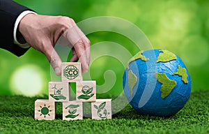 Wooden cube with eco symbol and paper globe on fertile soil background. Alter