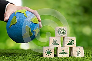 Wooden cube with eco symbol and paper globe on fertile soil background. Alter