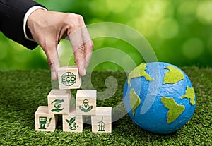 Wooden cube with eco symbol and paper globe on fertile soil background. Alter